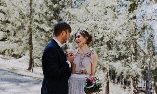 Blume wird übergeben, Dolomitenhütte, Hüttenshooting, Elopement, Hochzeit in Tirol, Braut lacht